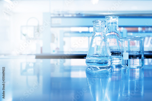 water in beaker and flask glass in chemistry blue science laboratory background photo