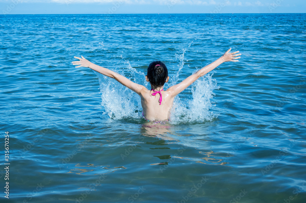 Teen girl splashing in the blue sea