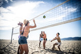Group of friends playing beach volley on the beach and having fun