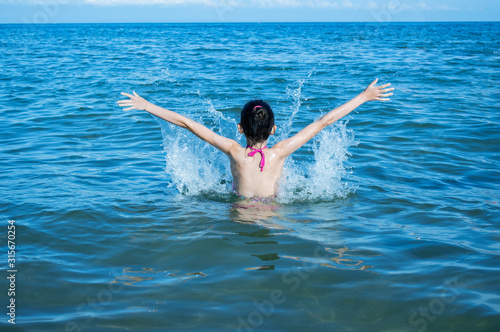 Teen girl splashing in the blue sea