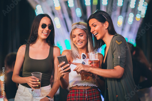 Three girls using phones in the amusement park
