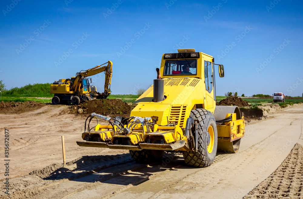 Plate compactor is mounted on road roller to compact soil at construction site Plate compactor is mounted on road roller to compact soil at construction site