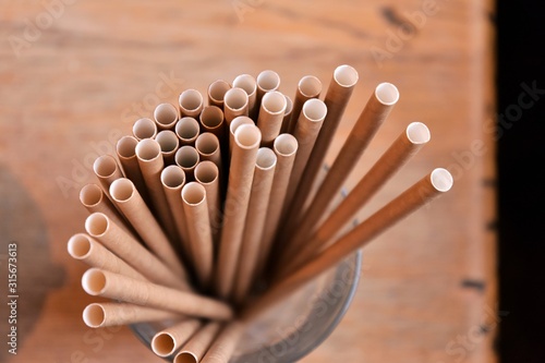 Eco friendly Reusable Straws in the cardboard cup with selective focus and blurred ba. Paper cocktail tubes. Kraft paper straw for drinking coffee or tea. Disposable cocktail tube.  photo