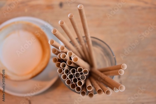 Eco friendly Reusable Straws in the cardboard cup with selective focus and blurred ba. Paper cocktail tubes. Kraft paper straw for drinking coffee or tea. Disposable cocktail tube. 