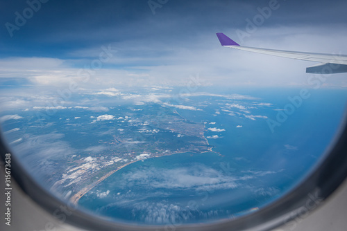 Wing of airplane flying above Hong Kong city background through the window.