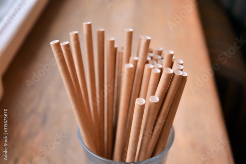 Eco friendly Reusable Straws in the cardboard cup with selective focus and blurred ba. Paper cocktail tubes. Kraft paper straw for drinking coffee or tea. Disposable cocktail tube.  photo