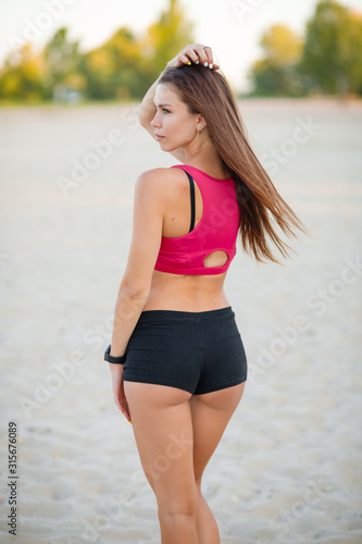 Beautiful sports girl with a smart watch and sportswear on the beach