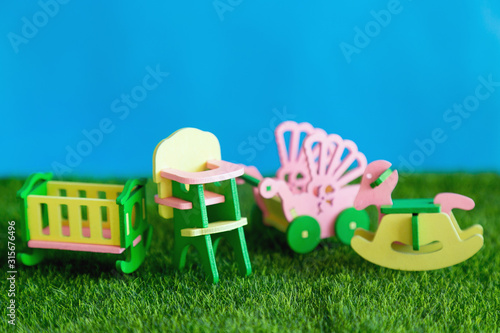 Children's furniture, crib, high chair, stroller on the green grass. Childhood in furniture. Conceptual photography