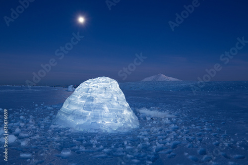 Iluminated igloo during a cold winter nights with bright moonshine photo