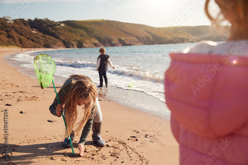 Children With Fishing Nets Playing On Shoreline Of Winter Beach