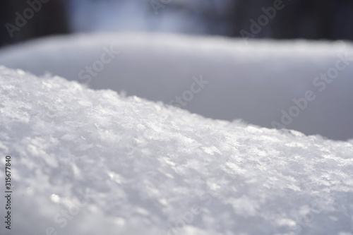 Snow with snowflakes close-up, soft focus forest background. Winter, Christmas, New Year concept. Product display, copy space