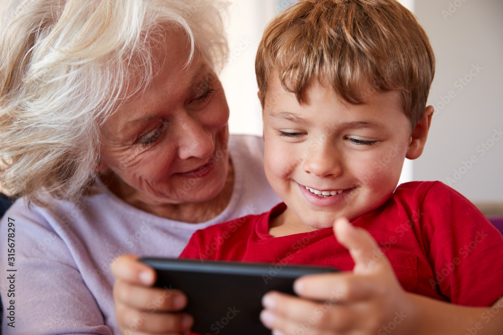 Grandmother Playing Video Game With Grandson On Mobile Phone At Home Grandmother Playing Video Game With Grandson On Mobile Phone At Home