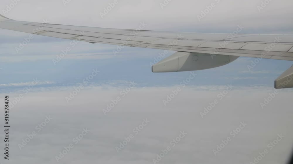 The plane flies clouds view on wing from the porthole The plane flies clouds view on wing from the porthole