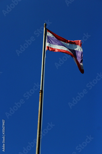 Thailand flag is waving with high pole with blue sky background. photo