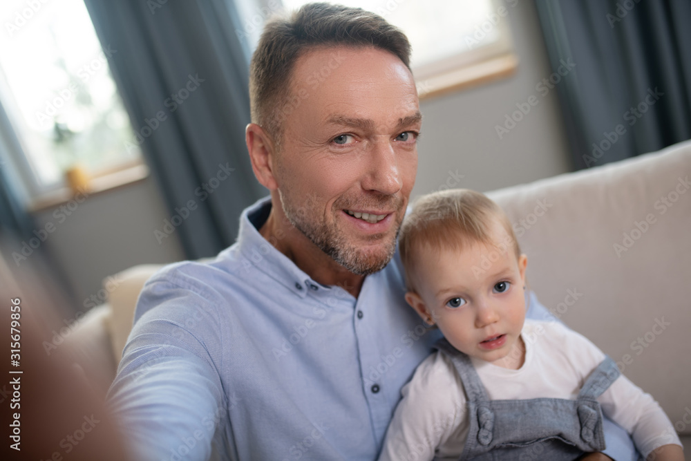 Obraz premium Mature father making selfie at home with his kid