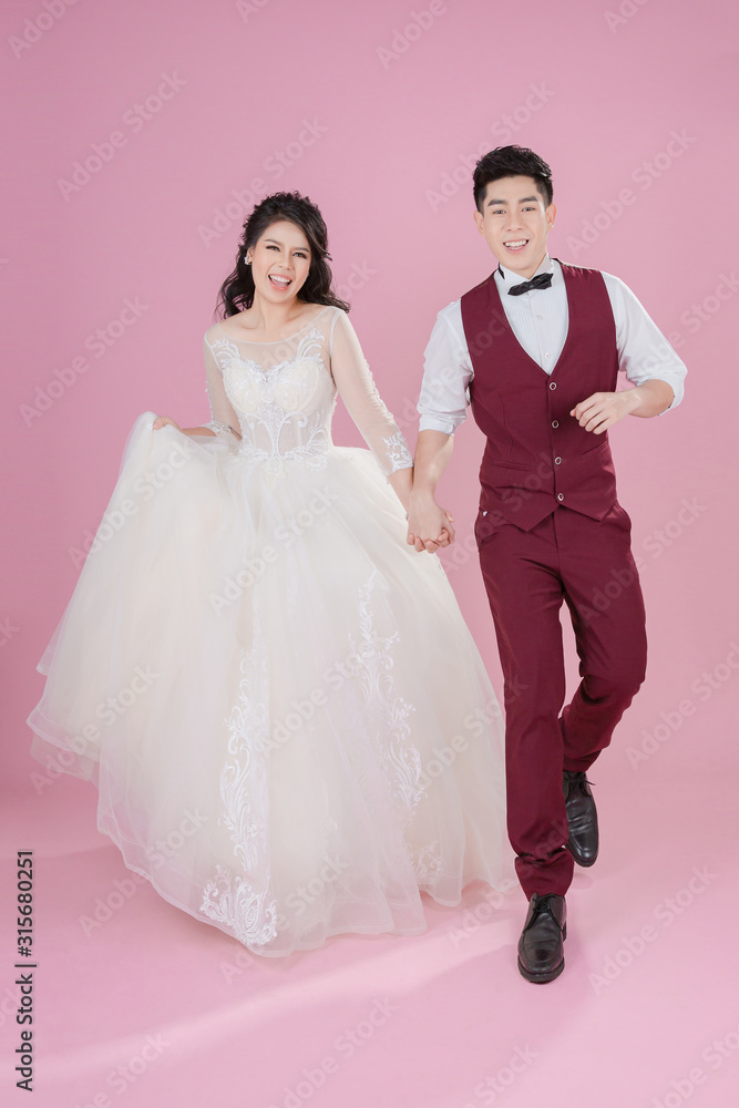 Happy young bride and groom on the pink background. Wedding couple, new family, wedding dress. Bridal wedding. Love concept