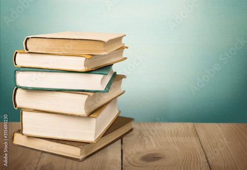Stack books with wooden desk on pastel background
