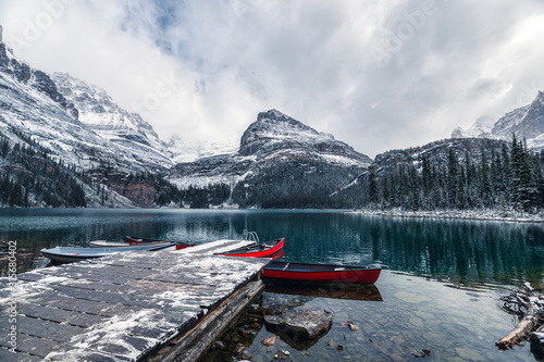 Rocky mountains with red canoe at wooden pier on Lake O'hara at Yoho national park