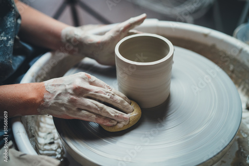 Obraz na plátne Closeup shot of female ceramic artist works on pottery wheel in studio space, Cr