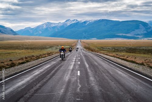 Motorcycle column traveling along the Chuysky tract at dawn, landscape with a highway. Russia, mountain Altai