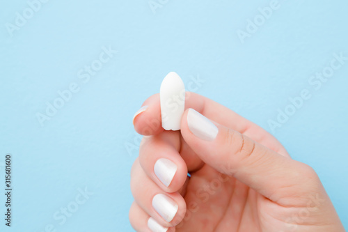 Young woman fingers holding white medical candle. Medical, pharmacy and healthcare concept. Closeup. Pastel blue background. photo