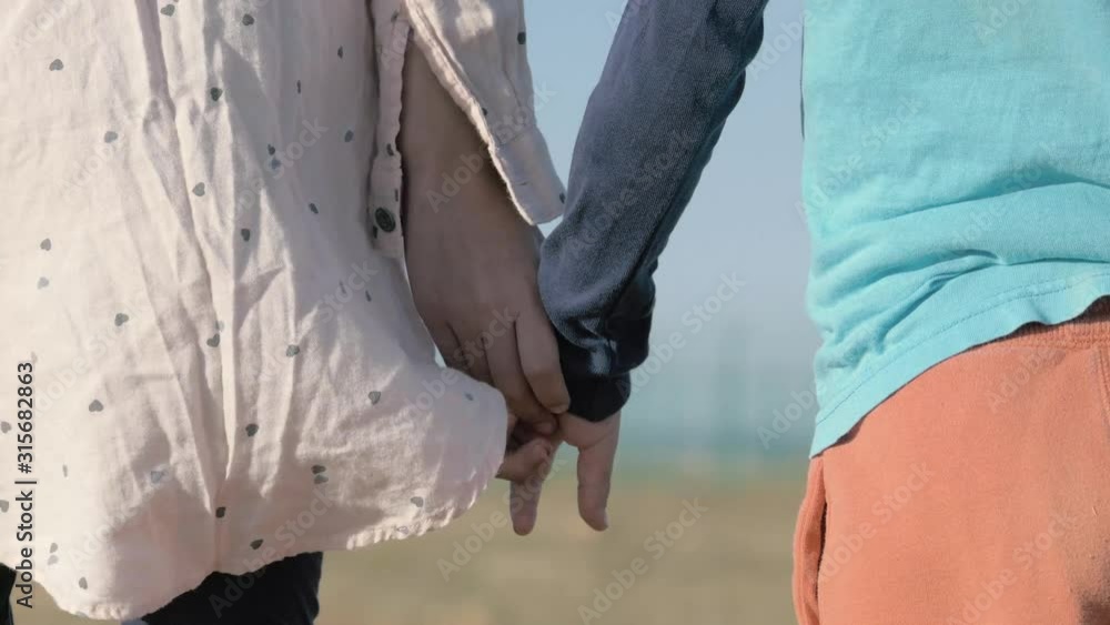 close-up children's hands holding each other. illegals Gypsies kids from dysfunctional family stand alone in field. Arabs refugees from middle East emigrate to Europe. close-up children's hands holding each other. illegals Gypsies kids from dysfunctional family stand alone in field. Arabs refugees from middle East emigrate to Europe.