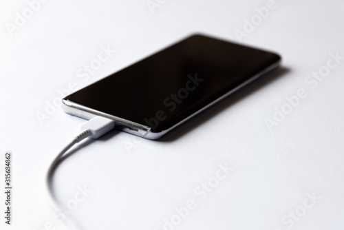 Soft focus of smart phone power charging on white background