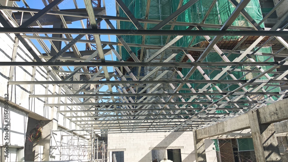 Obraz premium KUALA LUMPUR, MALAYSIA -JUNE 16, 2019: Lightweight roof trusses under construction at the construction site. Installed properly by workers to received the roof covering system. 
