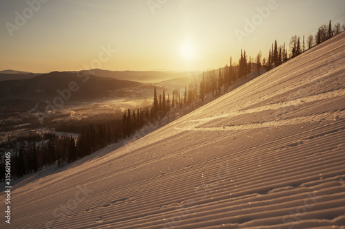 Snow surface on steep slope groomed and prepared for alpine skiing on sunrise. Mountain ski resort skyline view