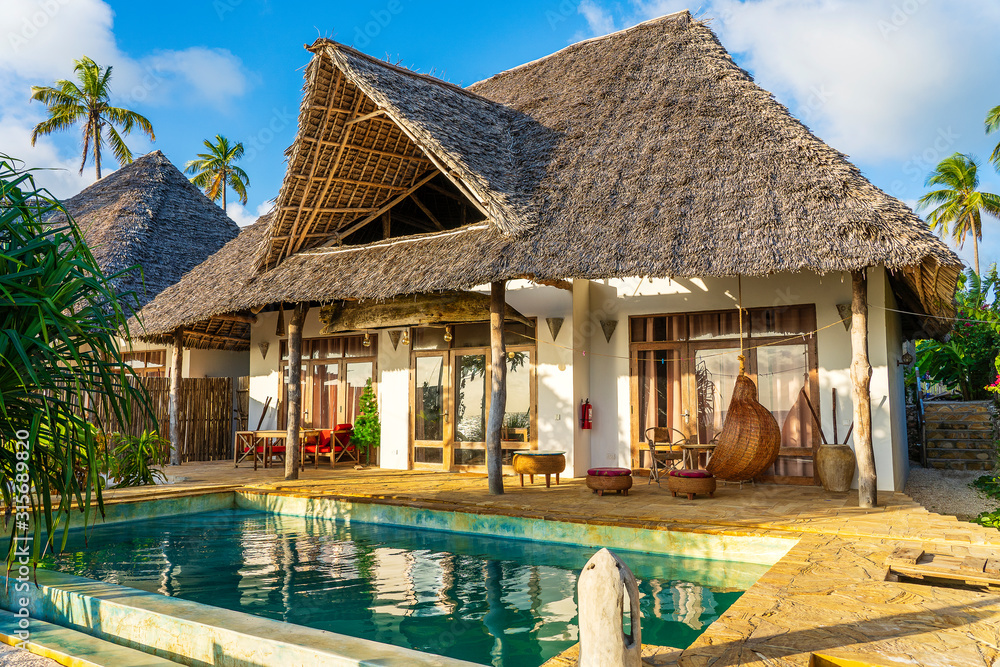 Morning view of a luxury villa on the tropical beach near sea on the island of Zanzibar, Tanzania, Africa - obrazy, fototapety, plakaty 