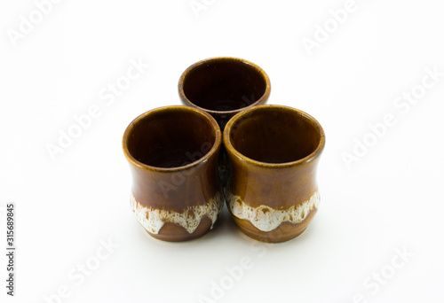 Three small brown ceramic glasses. Stand on a white background