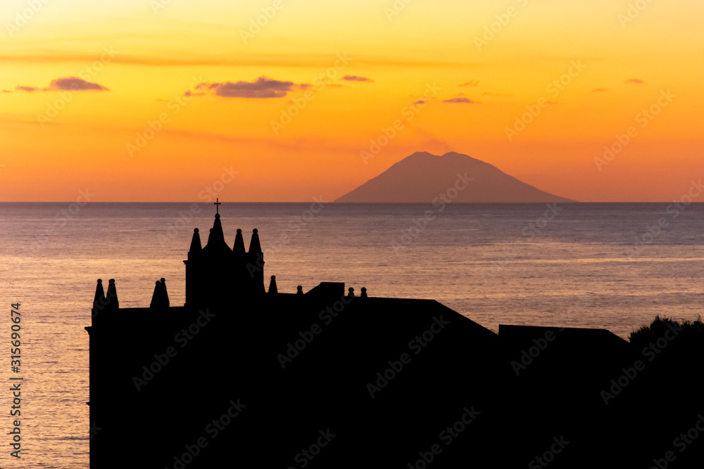 Obraz premium Tropea, Calabria, Italy: sunset with view of the Stromboli volcano and the Church of Santa Maria dell'Isola, the medieval shrine of the city built on the top of a small islet in the Tyrrhenian Sea
