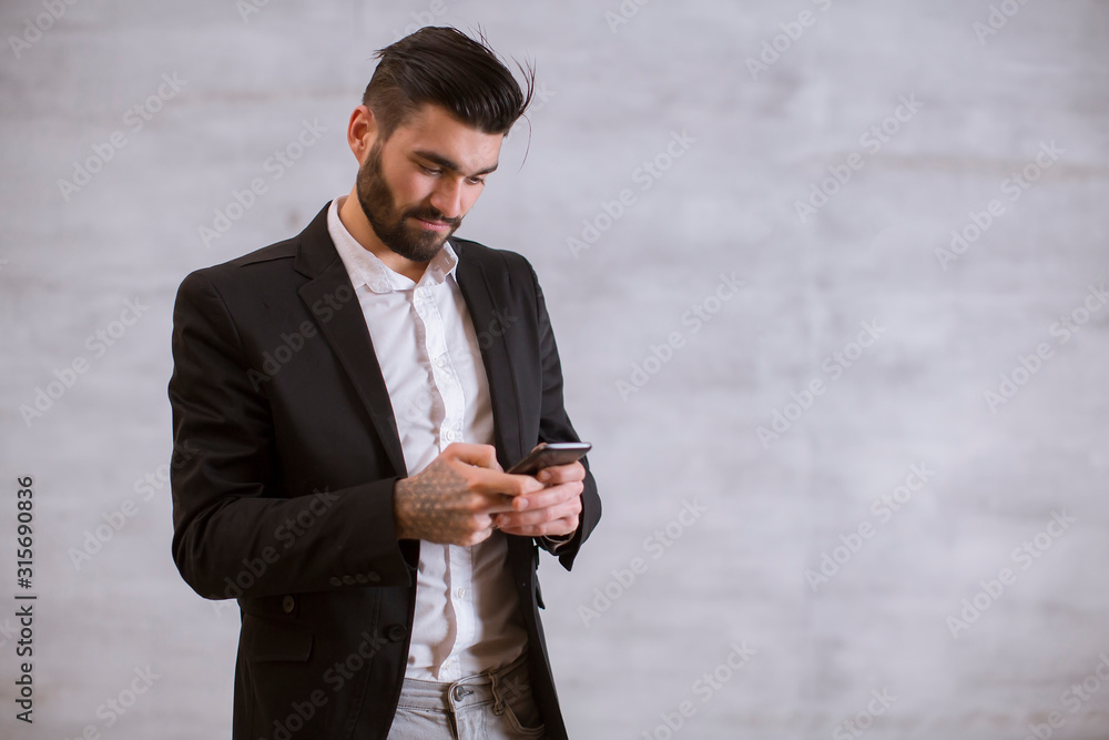 Young man with mobile phone by the wal Young man with mobile phone by the wal