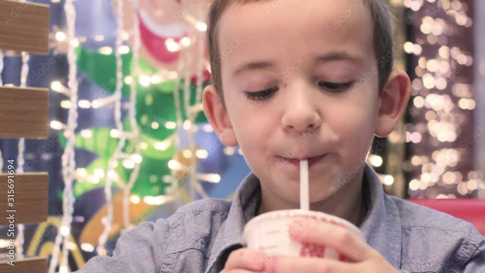 A boy in a cafe drinking a beverage through a straw A boy in a cafe drinking a beverage through a straw
