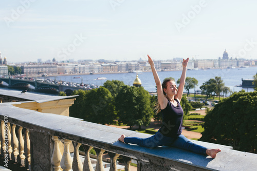 Young female doing yoga, standing on her hands on roof top in city center