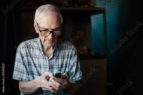 Elderly man using small cell phone at home