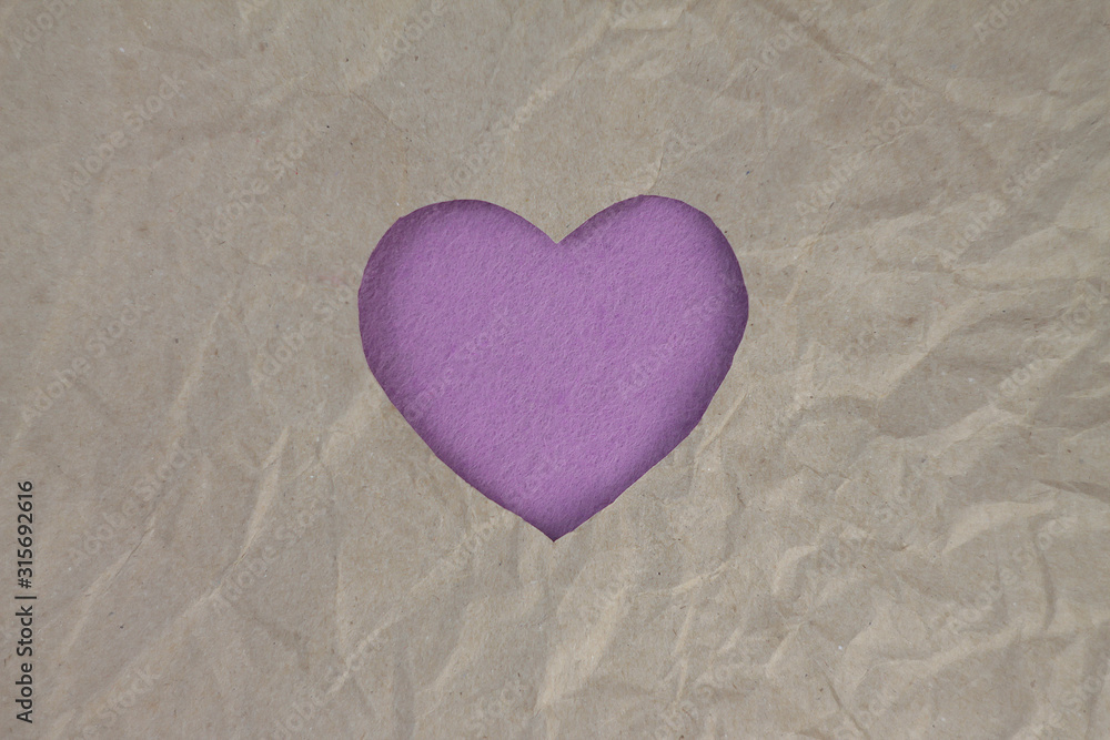 Fototapeta premium Violet felt heart on craft paper. Crumpled paper texture. Valentine's day stock photo for web, print and wallpaper.With empty space for text.