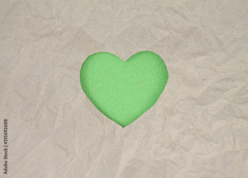 Fototapeta premium Green felt heart on craft paper. Crumpled paper texture. Valentine's day stock photo for web, print and wallpaper.With empty space for text.
