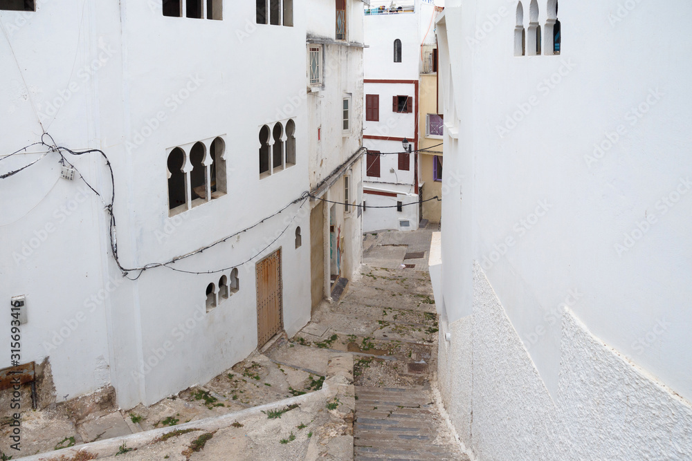 View of the one of the old white streets in the Tangier Medina quarter in Northern Morocco. A medina is typically walled, with many narrow and maze-like streets.