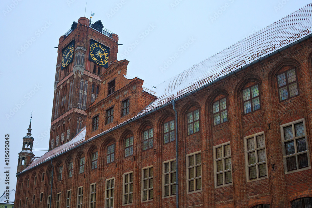 View of the gothic red bricks Torun City Hall on the Rynek Staromiejski street in the historic part of town in winter time.