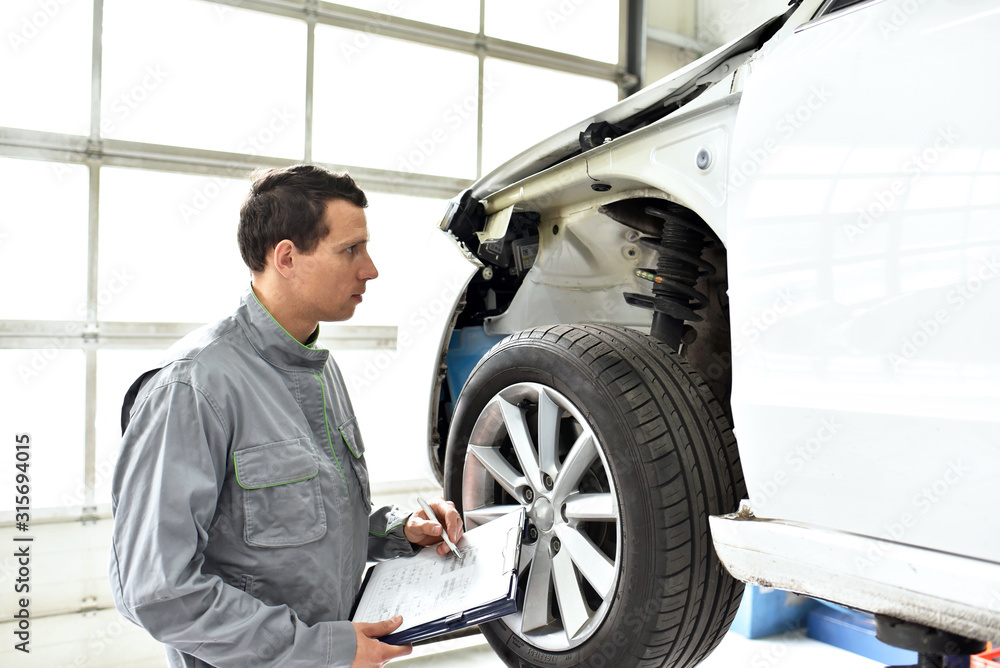 service and inspection of a car in a workshop - mechanic inspects the technology of a vehicle for function and safety service and inspection of a car in a workshop - mechanic inspects the technology of a vehicle for function and safety