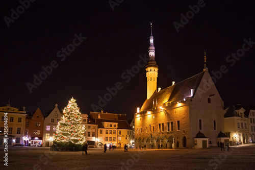 Night view of the Christmas tree near medieval The Tallinn Town Hall. Built in XIV century and firstly mentioned as consistorium in 1322, and in 1372 as town hall. Estonia.