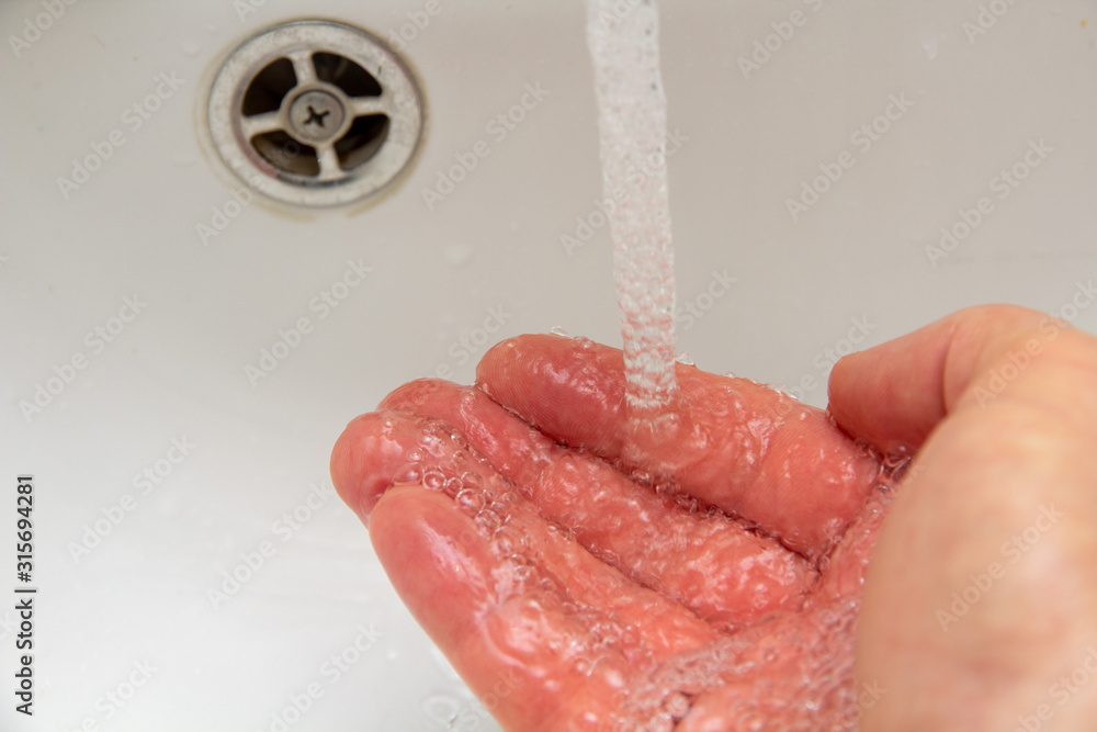 Fototapeta premium Mann hält seine Hand unter laufenden Wasserhahn