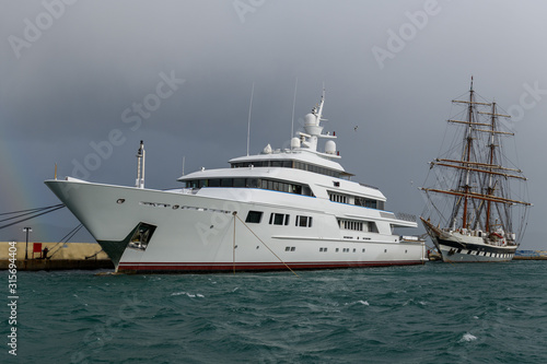 White luxury super yacht and sailing ship moored in marina. © Alexey Seafarer