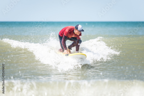 surf instructor surfing in action trying to push himself into a standing position.