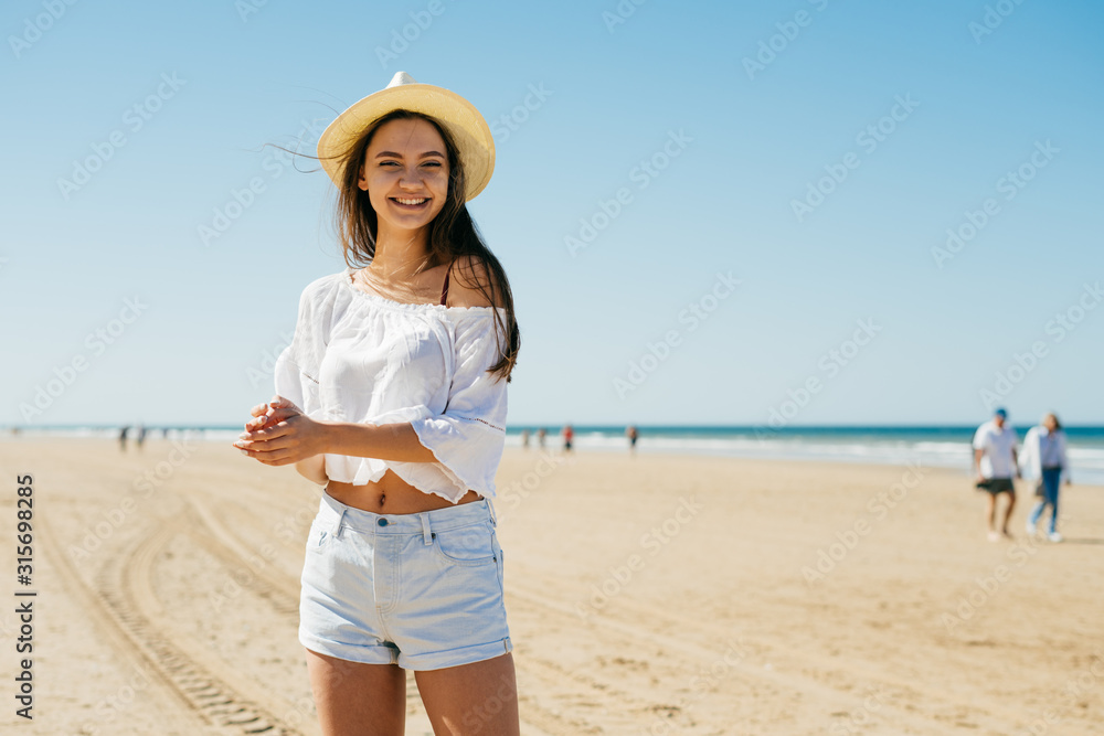 joyfully rubbing palms girl in a hat smiles on a sunny day against the background of the ocean joyfully rubbing palms girl in a hat smiles on a sunny day against the background of the ocean