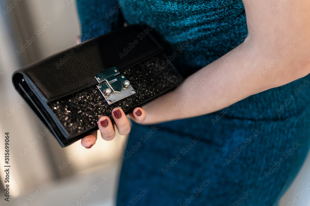 black leather female clutch with sequins. Brilliant, festive for a party. Holding girl