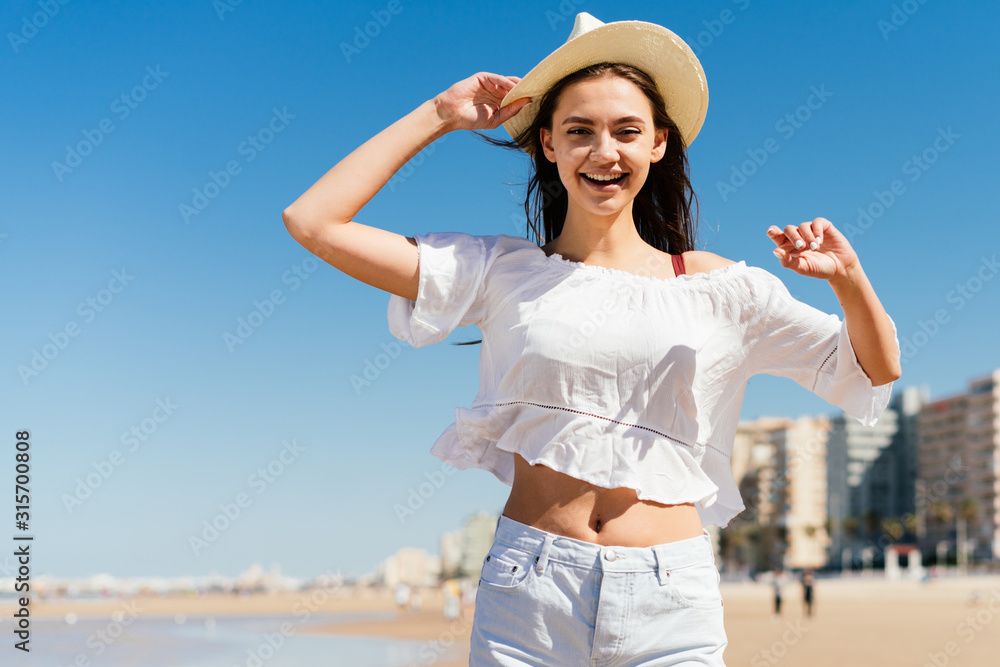 in delight holding the hat with one hand with the other the girl bent at the elbow dancing in the sand in delight holding the hat with one hand with the other the girl bent at the elbow dancing in the sand