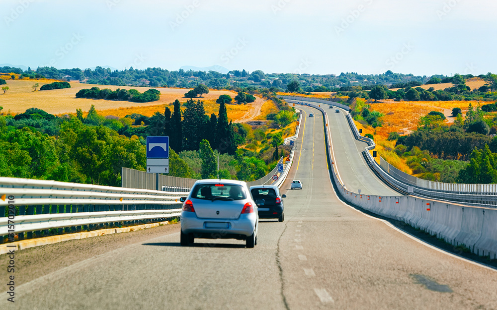 Car on the road at in Sardinia Island in Italy summer. Transport driving on the highway of Europe. View on motorway. Olbia province. Mixed media.