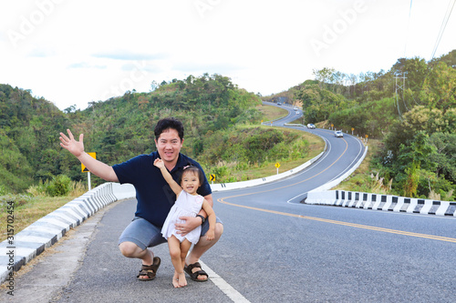 Father and his daughter on roadside with beautiful wavy road  in background